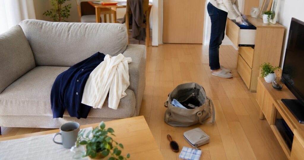 朝の支度で服やバッグが一時的に置かれたリビングのソファ周り